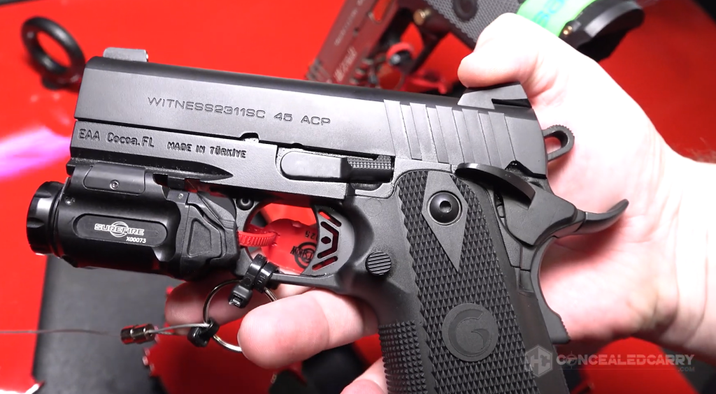 Close-up of the EAA Witness 2311 Brat .45 ACP pistol equipped with a SureFire weapon light, skeletonized trigger, and textured grips.
